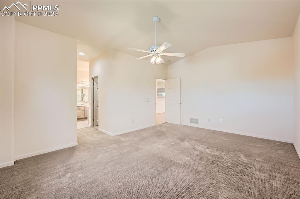 Image 12 of 27: Empty room featuring visible vents, baseboards, ceiling fan, vaulted ceilin