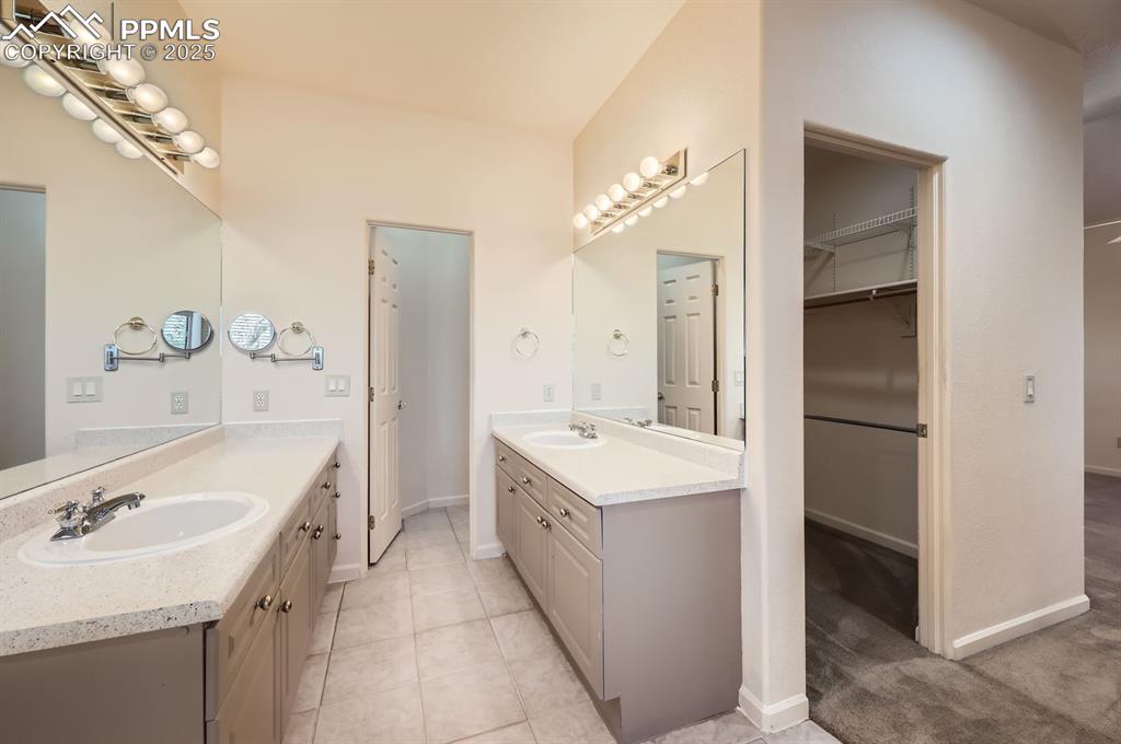 Image 14 of 27: Bathroom featuring two vanities, a sink, and a walk in closet