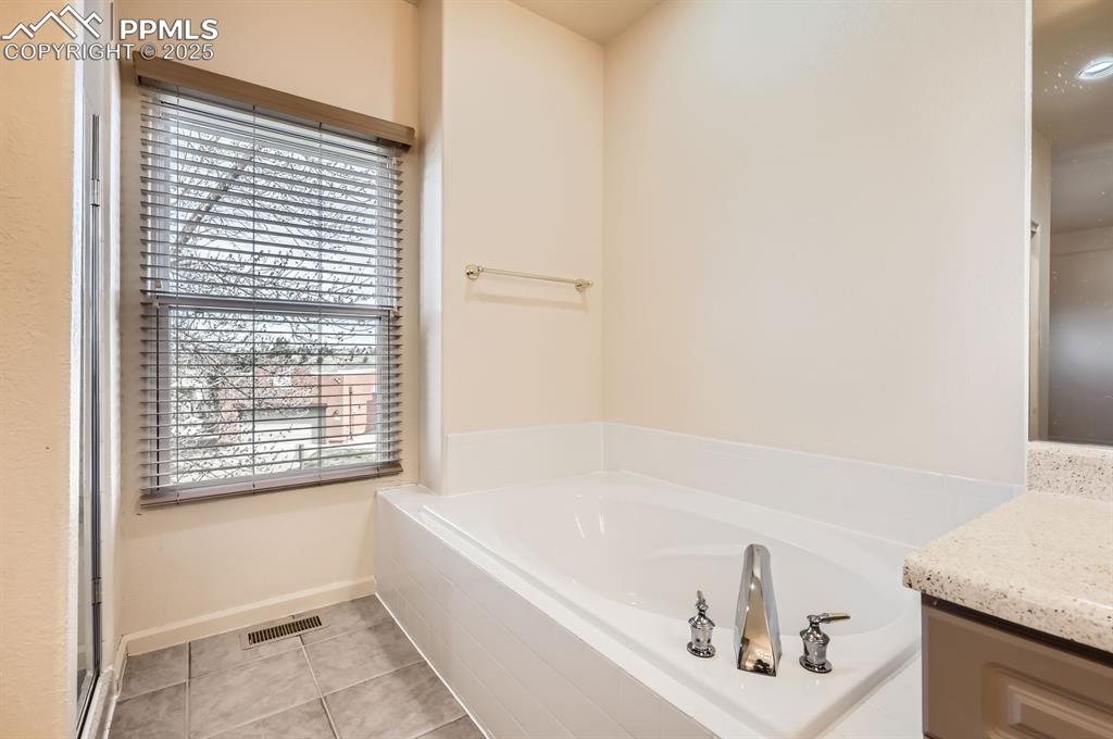 Image 15 of 27: Bathroom with a garden tub, vanity, visible vents, tile patterned floors, a