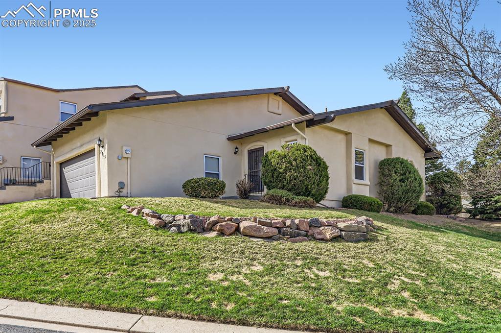 Image 2 of 27: View of front of property with a garage, a front yard, and stucco siding