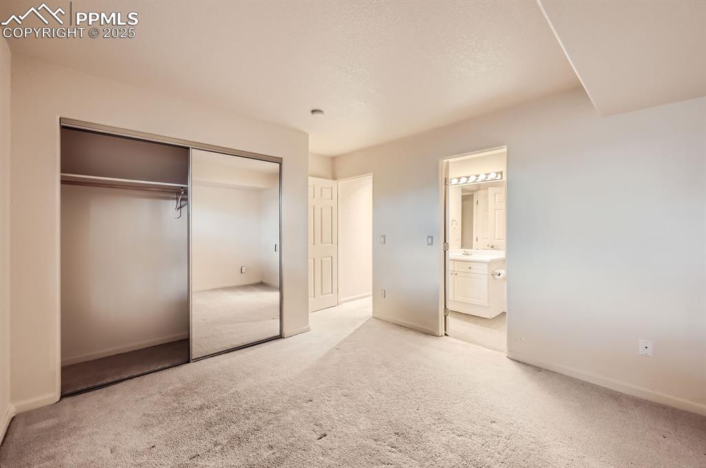 Image 20 of 27: Unfurnished bedroom with a closet, light colored carpet, baseboards, and en