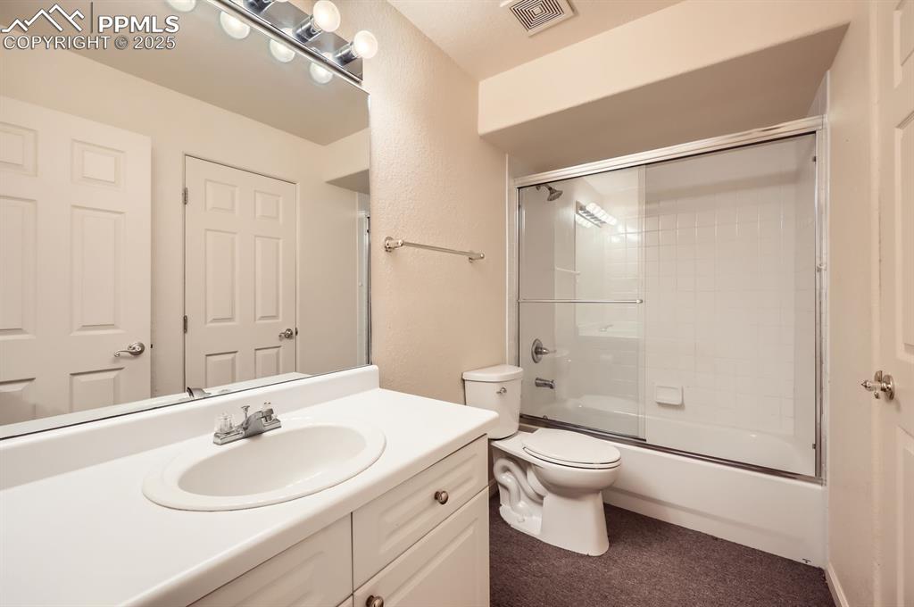 Image 21 of 27: Full bathroom with shower / bath combination with glass door, vanity, a tex
