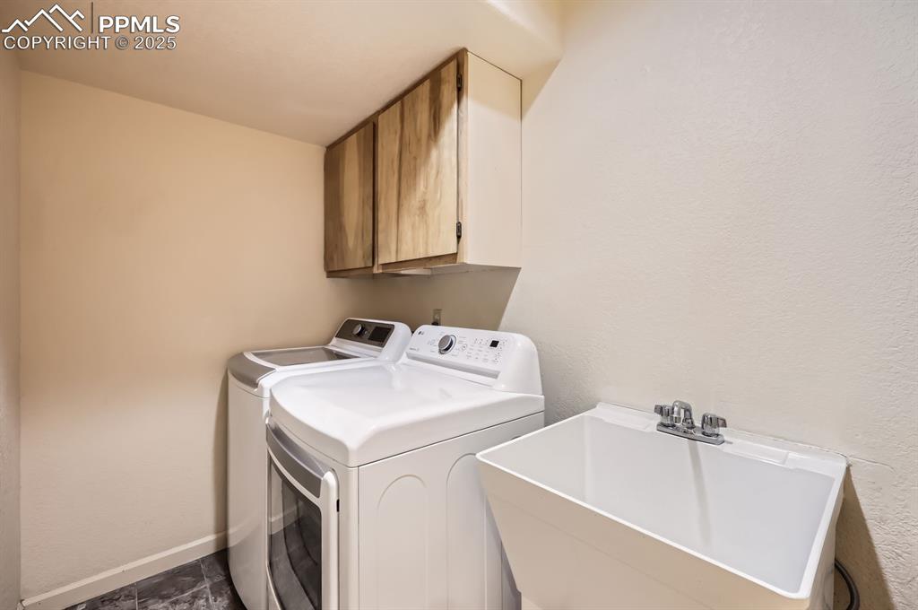 Image 22 of 27: Laundry area with a sink, washer and clothes dryer, cabinet space, and base
