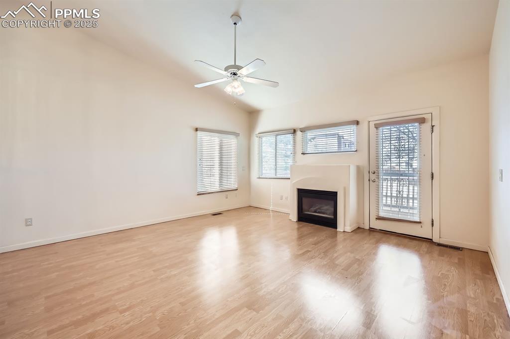 Image 3 of 27: Unfurnished living room featuring a glass covered fireplace, vaulted ceilin
