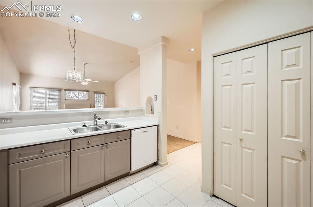 Image 5 of 27: Kitchen featuring vaulted ceiling, light countertops, a sink, white dishwas
