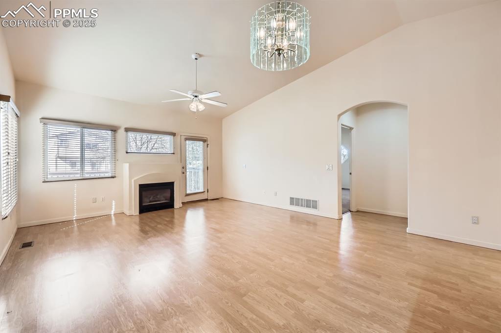 Image 7 of 27: Unfurnished living room with ceiling fan with notable chandelier, a firepla