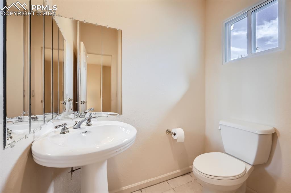 Image 9 of 27: Half bathroom with tile patterned floors, baseboards, a sink, and toilet