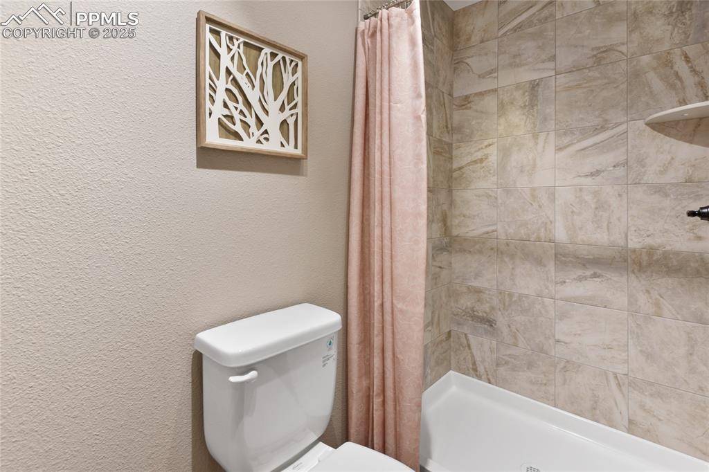 Image 23 of 44: Bathroom featuring a textured wall and a stall shower