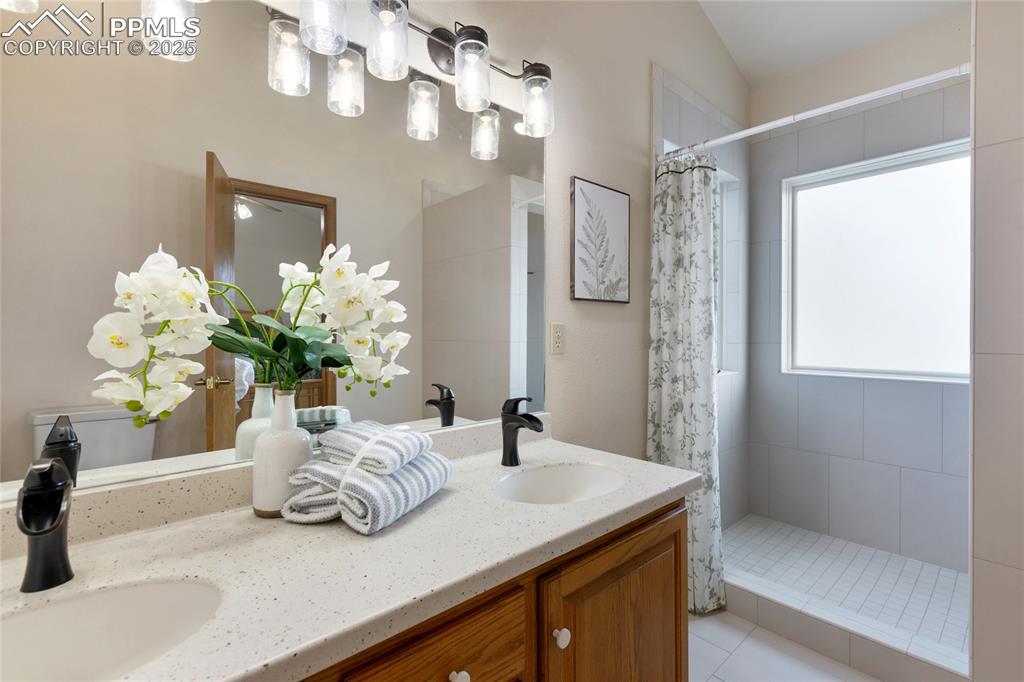 Image 28 of 44: En-suite with custom tile walk-in shower, frosted glass provides natural li