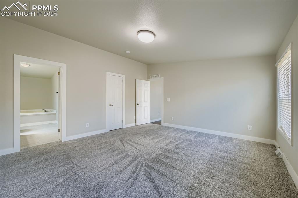 Image 19 of 28: Unfurnished bedroom with light colored carpet and ensuite bath
