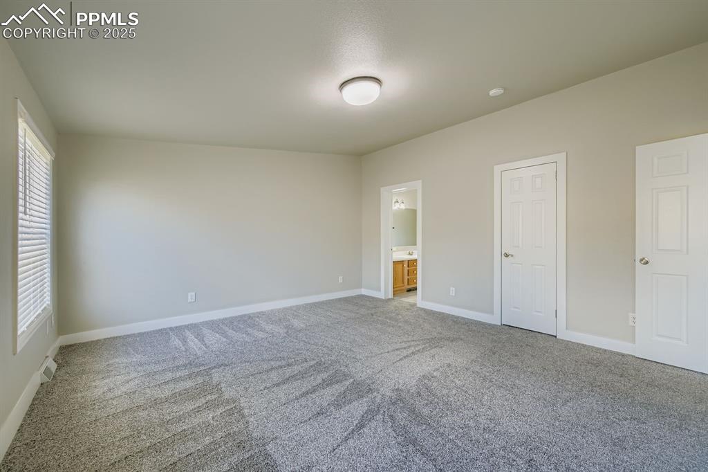 Image 20 of 28: Unfurnished bedroom with light carpet and connected bathroom