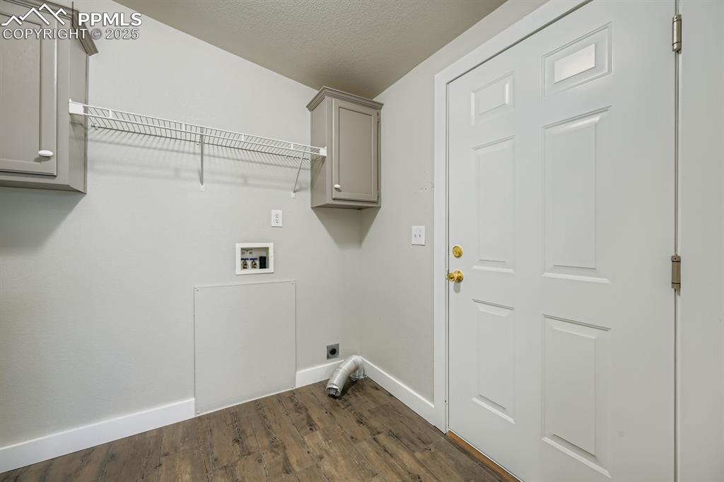 Image 24 of 28: Laundry area featuring dark wood-type flooring, electric dryer hookup, a te