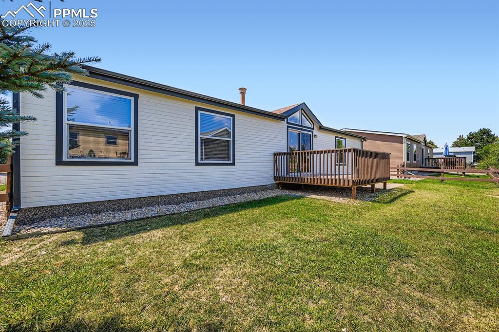 Image 25 of 28: Rear view of house with a wooden deck and a yard