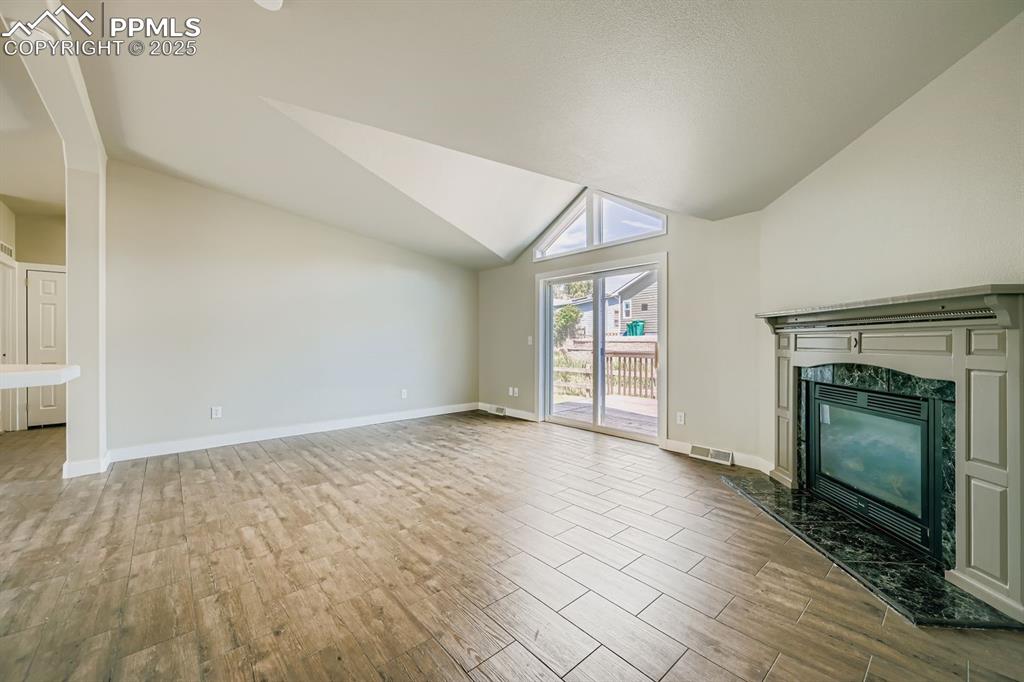 Image 7 of 28: Unfurnished living room featuring wood tiled floors, a high end fireplace, 