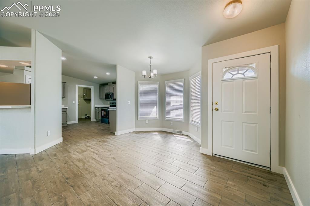 Image 8 of 28: Entryway featuring a chandelier and wood tiled floors