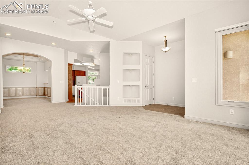 Image 13 of 35: Empty room featuring built in shelves, light colored carpet, lofted ceiling