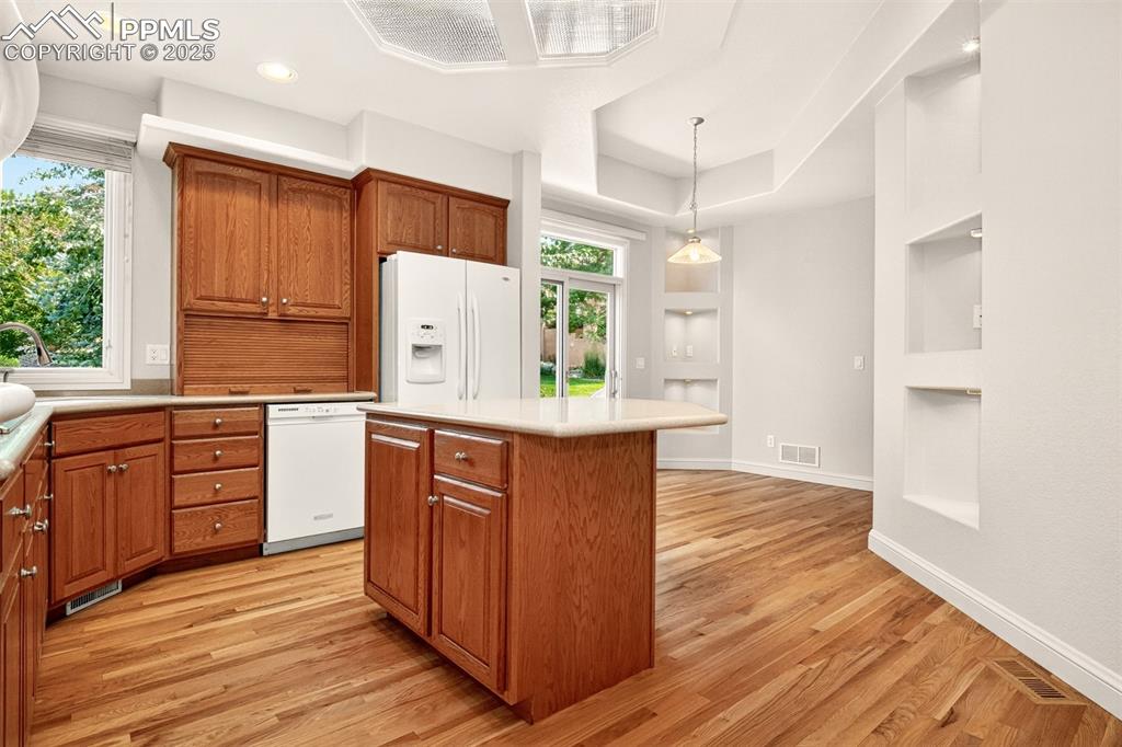 Image 15 of 35: Kitchen with brown cabinetry, white appliances, a kitchen island, built in