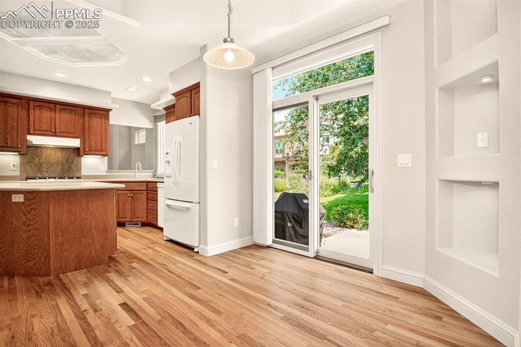 Image 19 of 35: Kitchen with light countertops, light wood-style flooring, decorative light