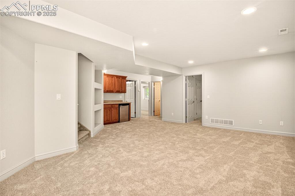 Image 21 of 35: Family room with wet bar and newly laid carpeting