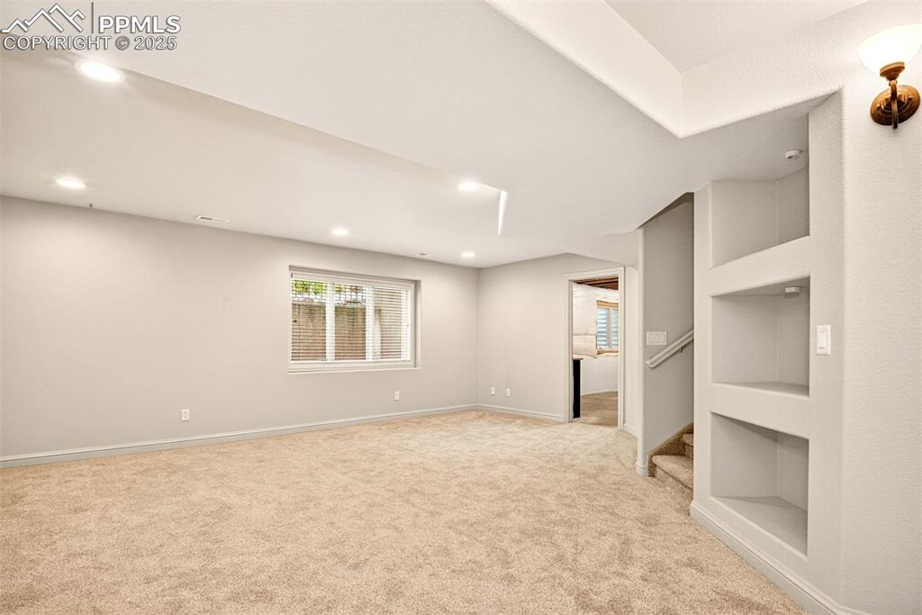 Image 22 of 35: Family room with newly laid carpet, and built in shelves with lighting