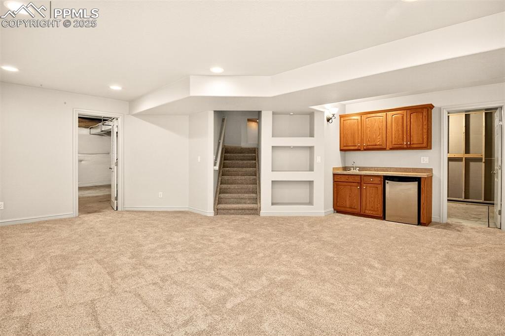 Image 23 of 35: Unfurnished living room featuring recessed lighting, light carpet, stairs,
