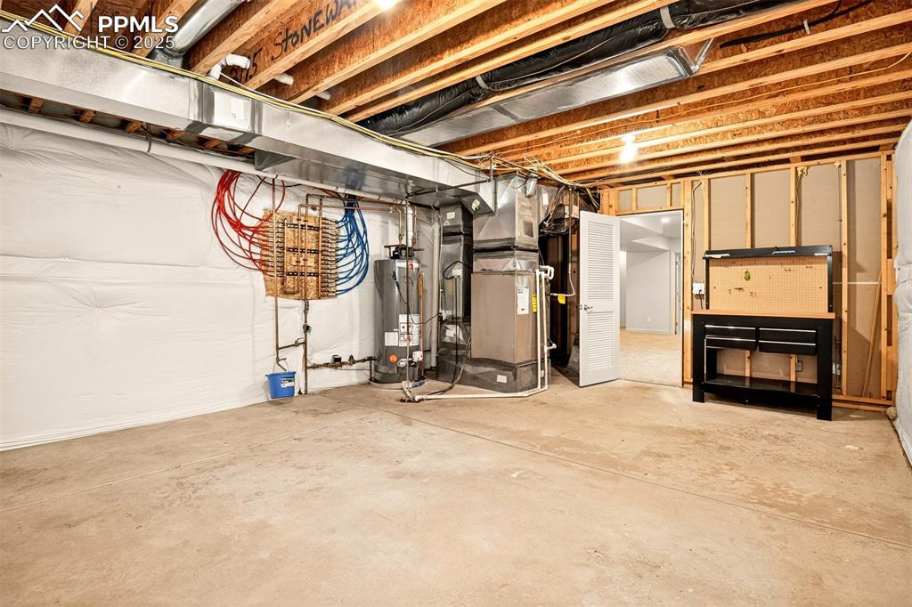 Image 25 of 35: Unfinished below grade area with heating unit and water heater