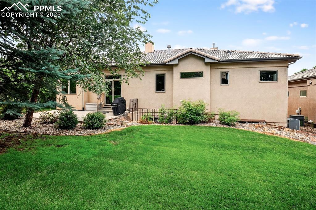 Image 33 of 35: Rear view of house featuring a patio area, stucco siding, a yard, a chimney