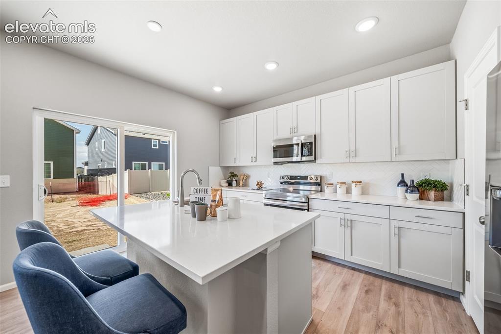 Image 16 of 23: Contemporary kitchen featuring white shaker cabinetry and stainless steel a