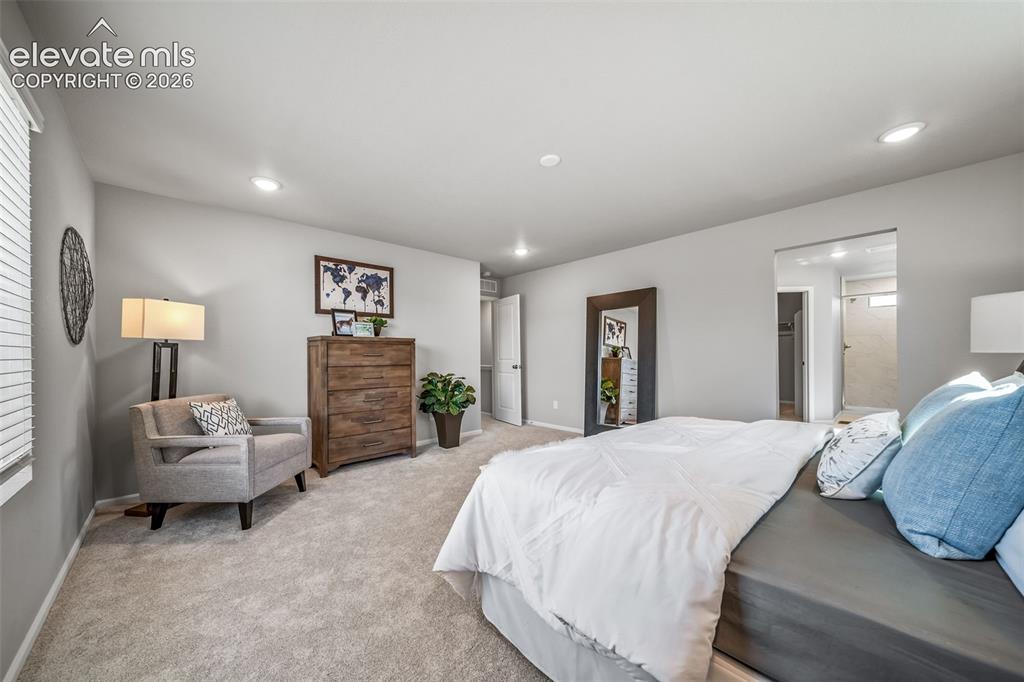 Image 21 of 23: Spacious bedroom featuring plush carpeting, recessed lighting, and a neutra