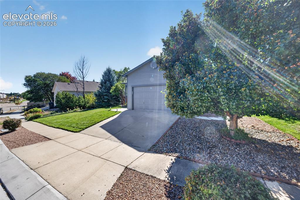 Image 3 of 31: Oversized two-car garage with professional landscaping and decorative rock