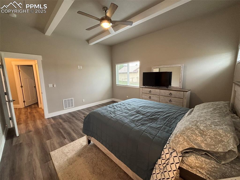 Image 12 of 29: Bedroom featuring beam ceiling, dark wood-style flooring, and ceiling fan