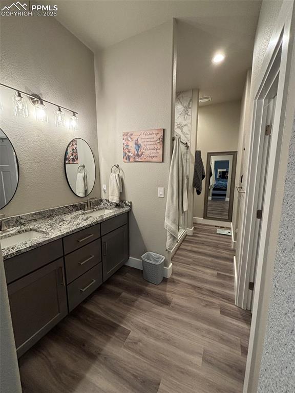 Image 13 of 29: Full bathroom with a textured wall, double vanity, a shower stall, dark woo