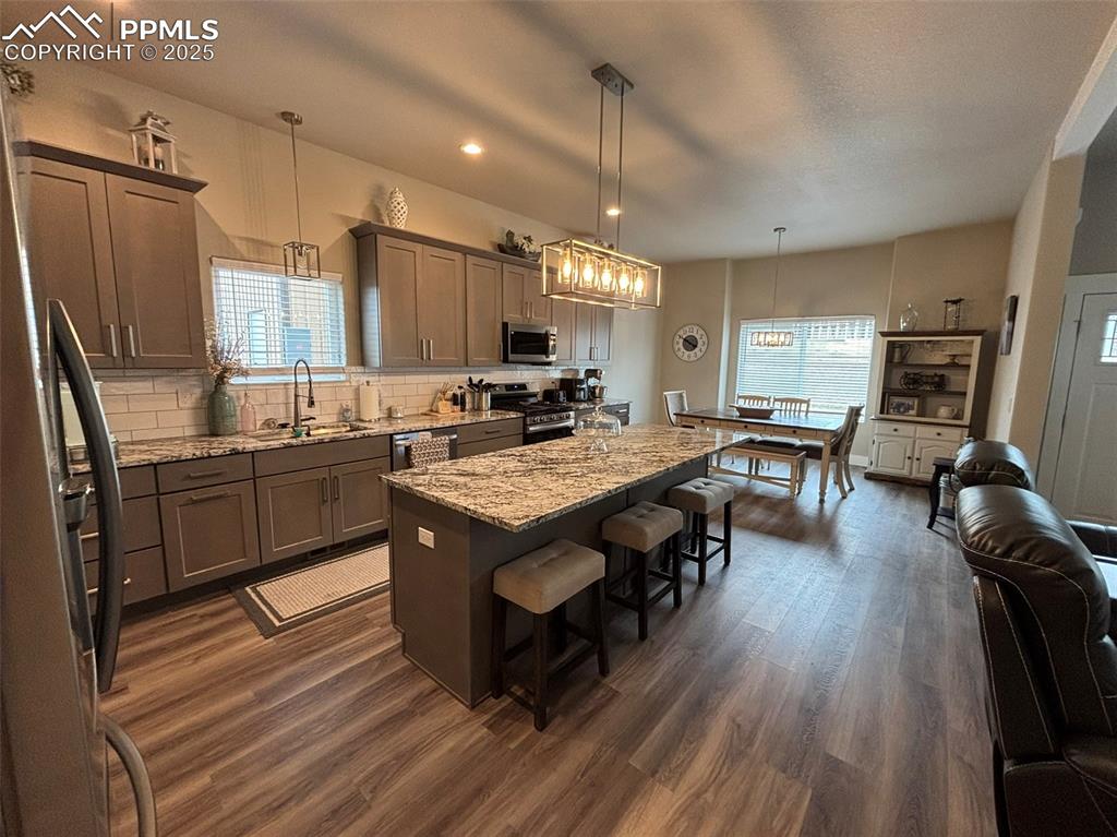Image 7 of 29: Kitchen with a kitchen breakfast bar, light stone counters, tasteful backsp