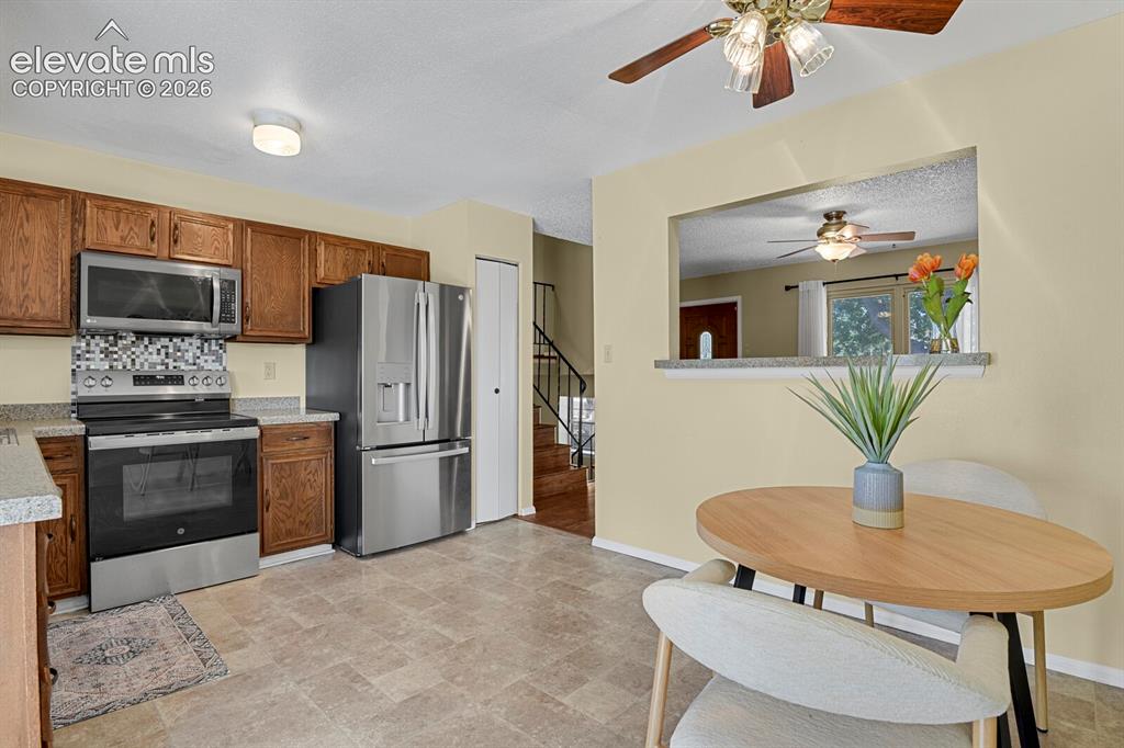 Image 10 of 28: Kitchen featuring wood cabinetry, stainless steel appliances, a multi-tone