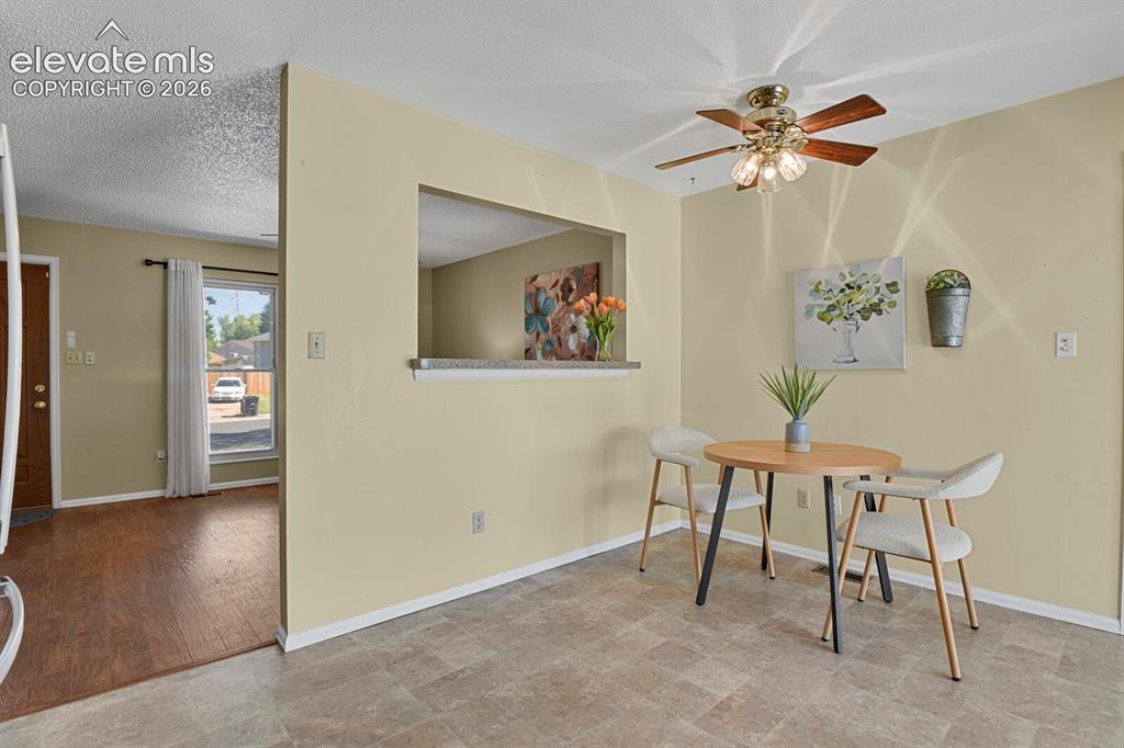 Image 11 of 28: Dining area featuring a ceiling fan with integrated lighting, a pass-throug