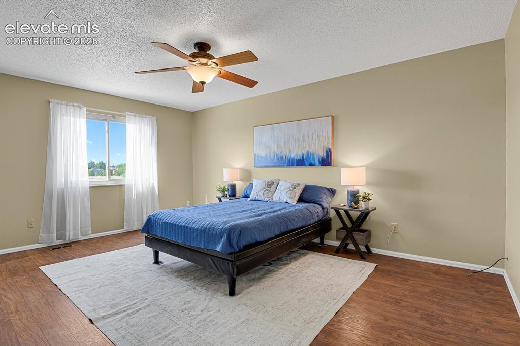 Image 16 of 28: Spacious room featuring wood-finish flooring, a ceiling fan with integrated
