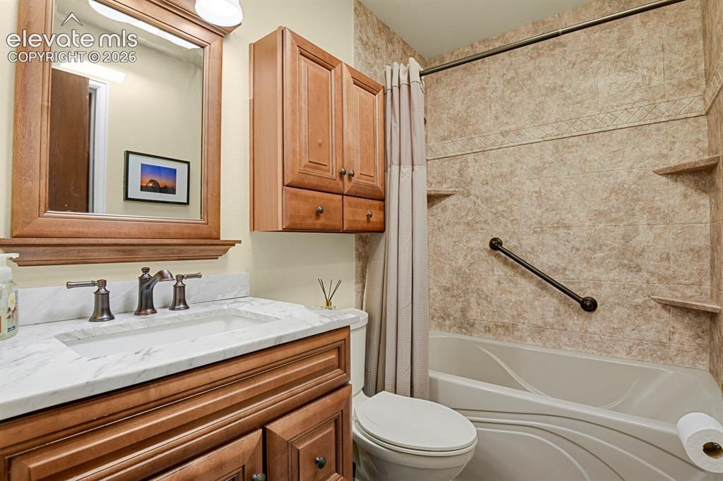 Image 18 of 28: Bathroom featuring a single vanity with a white countertop and bronze-finis