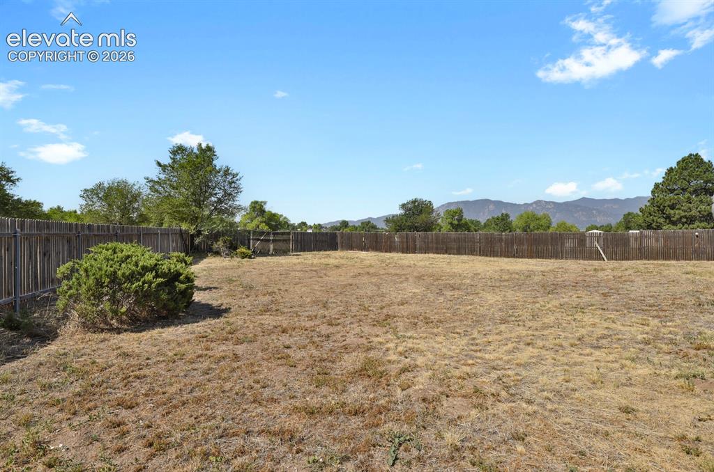 Image 26 of 28: Spacious outdoor area featuring a full privacy fence and mature landscaping