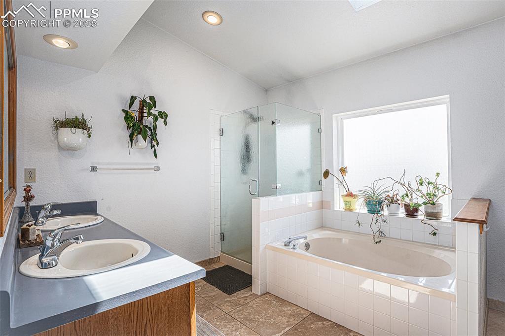 Image 10 of 27: Full bathroom featuring a garden tub, a stall shower, double vanity, and ti