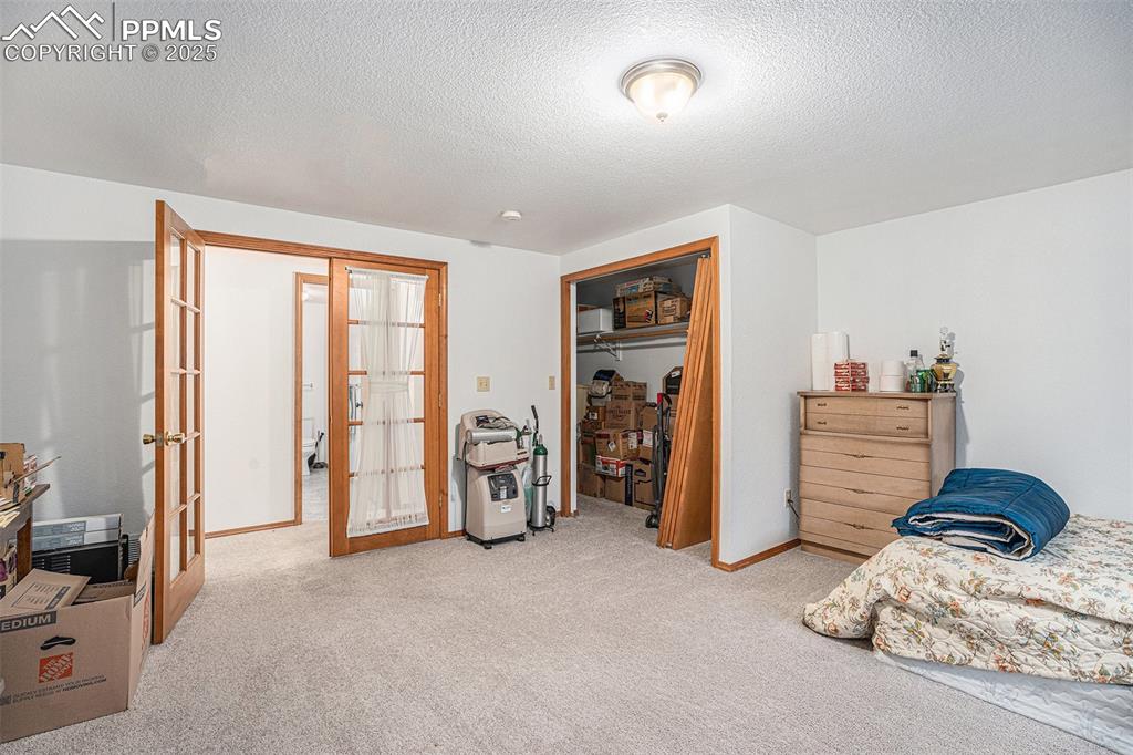 Image 17 of 27: Carpeted bedroom featuring french doors, a closet, and a textured ceiling
