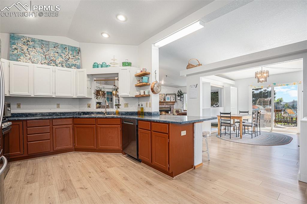 Image 2 of 27: Kitchen with dishwasher, a peninsula, vaulted ceiling, dark countertops, an