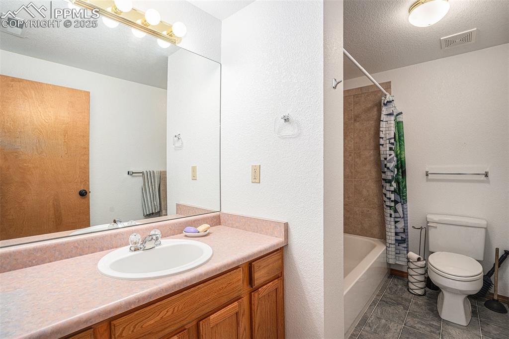 Image 21 of 27: Bathroom featuring vanity, shower / bath combo with shower curtain, and a t