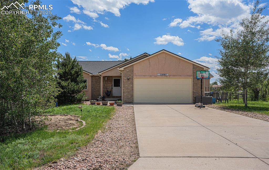 Image 24 of 27: Single story home with an attached garage, concrete driveway, and brick sid