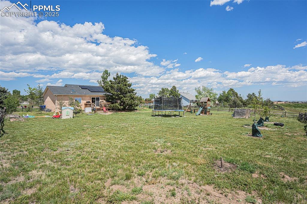 Image 25 of 27: View of yard featuring a trampoline and a playground