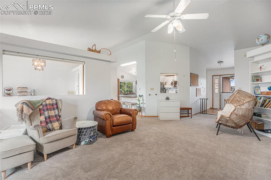Image 4 of 27: Carpeted living area featuring ceiling fan and lofted ceiling
