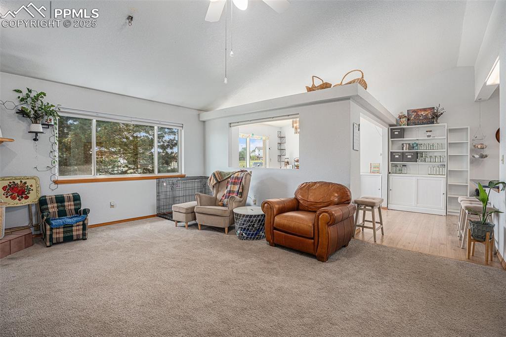 Image 5 of 27: Living area featuring lofted ceiling, carpet, a ceiling fan, and wood finis
