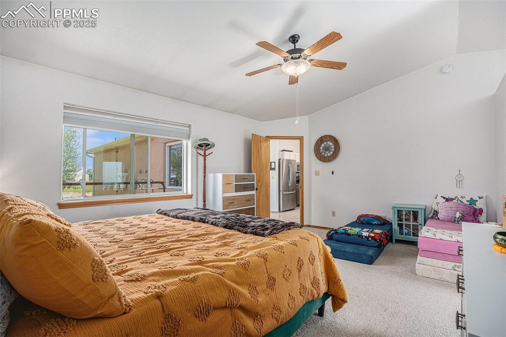 Image 9 of 27: Bedroom featuring freestanding refrigerator, light carpet, lofted ceiling,