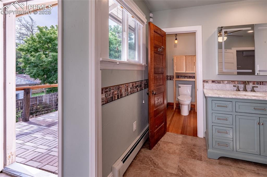 Image 18 of 49: Bathroom with a baseboard radiator, under tile floor heating, lighted vanit