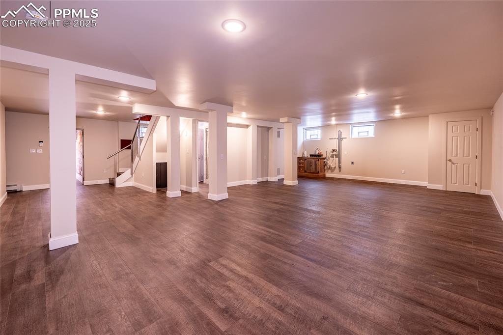 Image 22 of 49: Below grade area with stairway, dark wood-type flooring, and baseboard heat