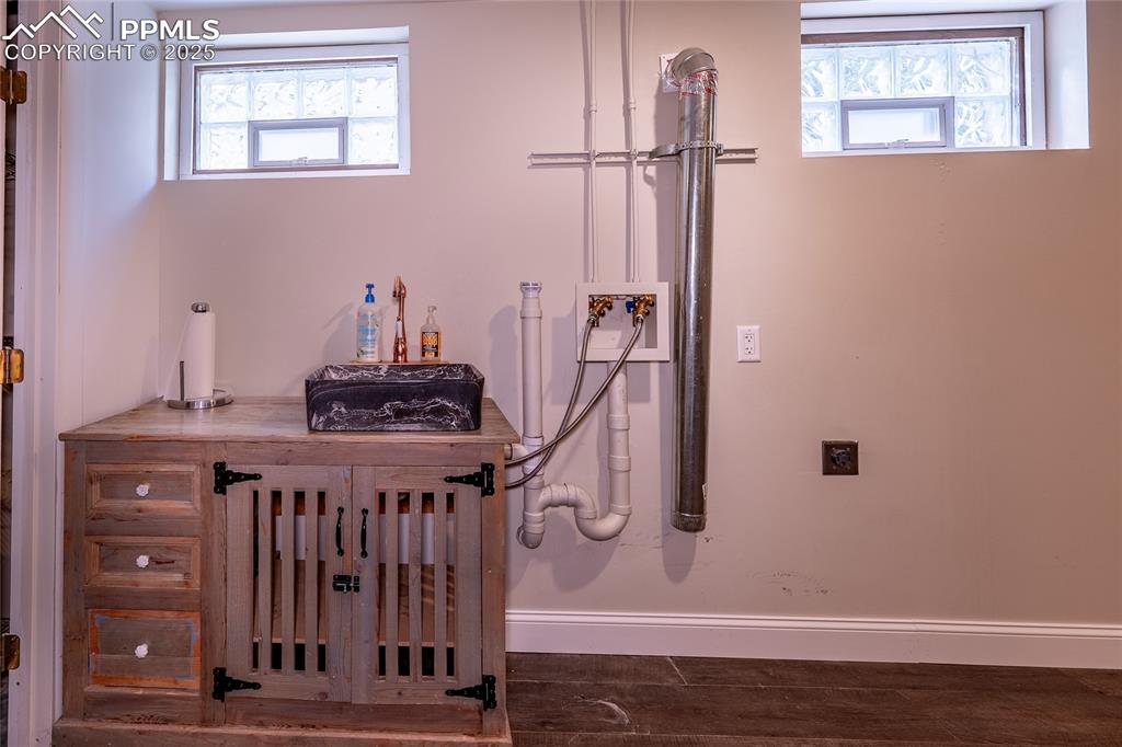 Image 25 of 49: Laundry sink is built on antique cabinet and features copper fixtures.